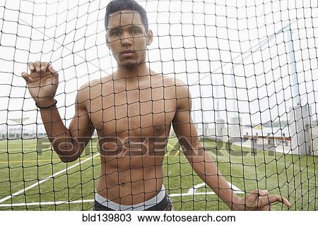 Man standing in soccer net on field View Large Photo Image Stock Image - Man standing in soccer net on field. Fotosearch
