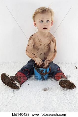 Messy Caucasian boy playing with mud on white carpet View Large Photo Image Stock Photo - Messy Caucasian boy playing with mud on white carpet. Fotosearch