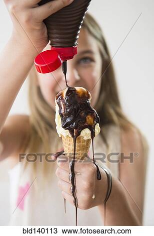 Messy Caucasian girl pouring chocolate syrup on ice cream cone View Large Photo Image Stock Image - Messy Caucasian girl pouring chocolate syrup on ice cream cone. Fotosearch