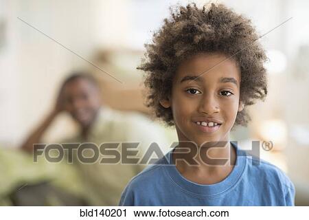 Stock Image - Mixed race boy smiling in living room. Fotosearch
