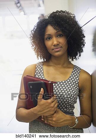 Stock Image - Mixed race businesswoman carrying digital tablet. Fotosearch