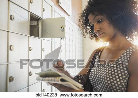 Stock Photo - Mixed race businesswoman checking mailbox. Fotosearch