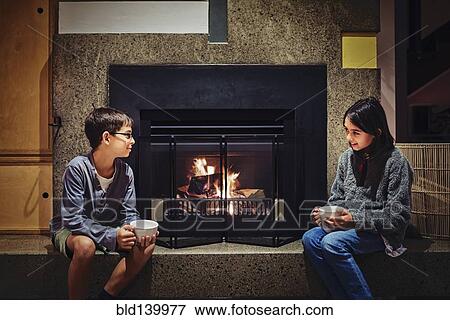 Mixed race children having hot drink together near fireplace View Large Photo Image Stock Photo - Mixed race children having hot drink together near fireplace. Fotosearch