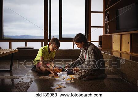 Stock Image - Mixed race children playing together on living room floor. Fotosearch