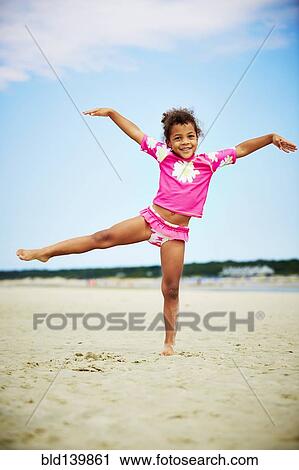 Stock Image - Mixed race girl posing on beach. Fotosearch