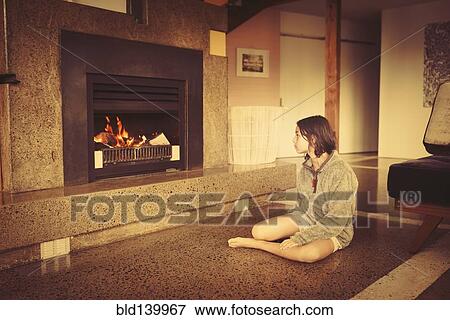 Mixed race girl relaxing by fireplace in living room View Large Photo Image Stock Photo - Mixed race girl relaxing by fireplace in living room. Fotosearch