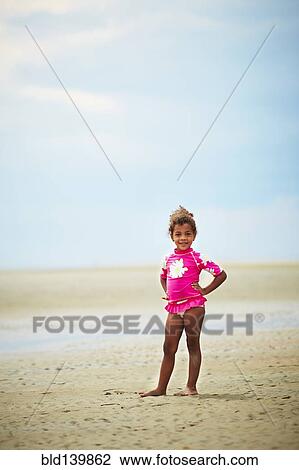 Stock Image - Mixed race girl standing on beach. Fotosearch