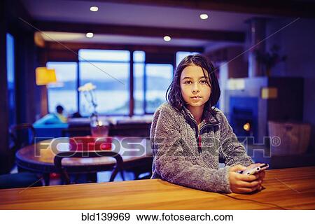 Stock Photo - Mixed race girl using cell phone at table. Fotosearch