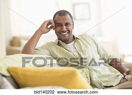 Stock Image - Mixed race man smiling in living room. Fotosearch