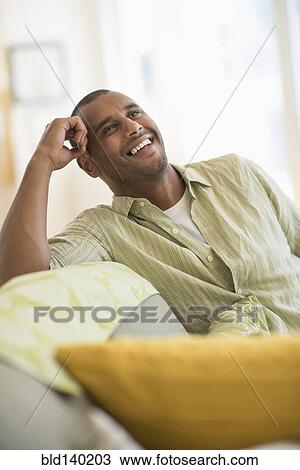 Mixed race man smiling in living room View Large Photo Image Stock Image - Mixed race man smiling in living room. Fotosearch