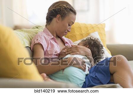 Mixed race mother nursing daughter in living room View Large Photo Image Stock Photo - Mixed race mother nursing daughter in living room. Fotosearch
