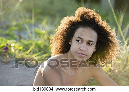 Mixed race teenage boy sitting on beach View Large Photo Image Picture - Mixed race teenage boy sitting on beach. Fotosearch