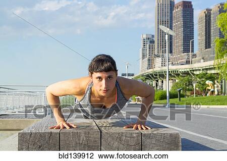 Mixed race woman doing push ups near city street View Large Photo Image Stock Image - Mixed race woman doing push ups near city street . Fotosearch