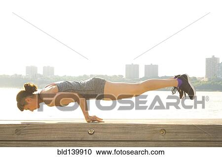 Stock Image - Mixed race woman exercising at urban waterfront. Fotosearch