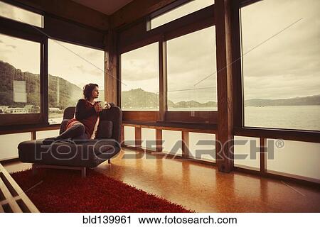 Mixed race woman looking out window of modern house View Large Photo Image Stock Image - Mixed race woman looking out window of modern house. Fotosearch