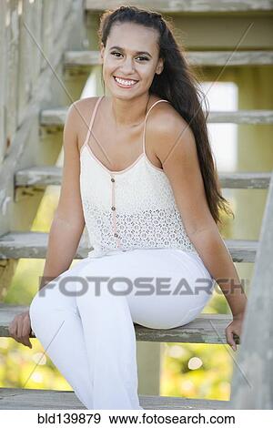 Stock Photo - Mixed race woman sitting on wooden steps. Fotosearch
