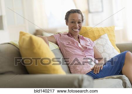 Mixed race woman smiling on sofa View Large Photo Image Stock Photo - Mixed race woman smiling on sofa. Fotosearch