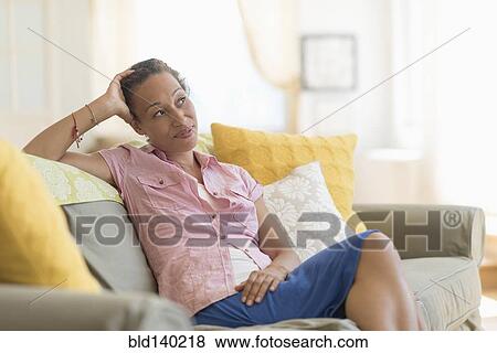 Stock Photo - Mixed race woman smiling on sofa. Fotosearch