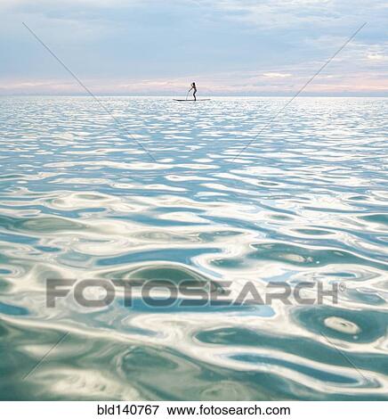 Mixed race woman standing on paddleboard in ocean View Large Photo Image Stock Photo - Mixed race woman standing on paddleboard in ocean. Fotosearch