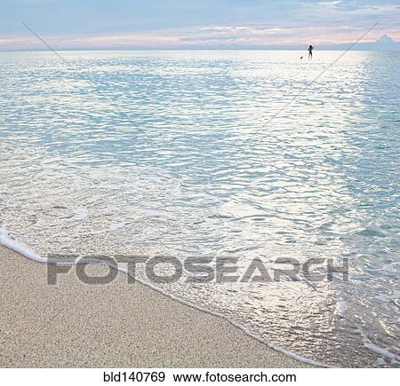 Mixed race woman standing on paddleboard in ocean View Large Photo Image Stock Photo - Mixed race woman standing on paddleboard in ocean. Fotosearch
