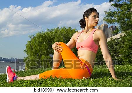 Stock Photo - Mixed race woman stretching in urban park. Fotosearch