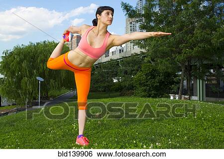 Stock Photograph - Mixed race woman stretching in urban park. Fotosearch