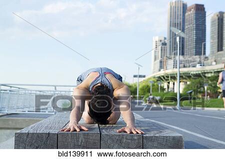 Stock Image - Mixed race woman stretching near city street. Fotosearch