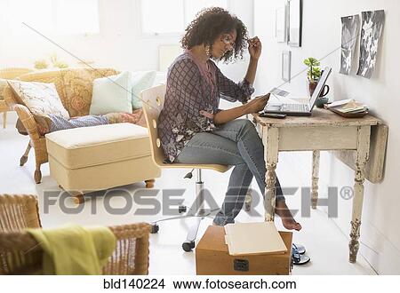 Mixed race woman using laptop in living room View Large Photo Image Picture - Mixed race woman using laptop in living room. Fotosearch