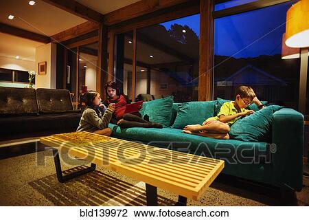 Stock Image - Mother and children relaxing together in modern living room. Fotosearch