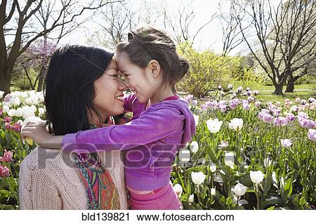 Stock Image - Mother and daughter rubbing noses in park. Fotosearch