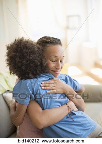Mother and son hugging on sofa in living room View Large Photo Image Stock Image - Mother and son hugging on sofa in living room. Fotosearch