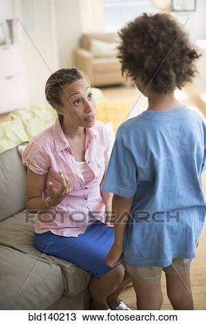Mother talking to son in living room View Large Photo Image Stock Image - Mother talking to son in living room. Fotosearch