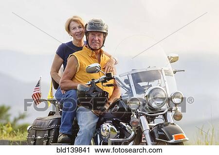 Stock Image - Older Caucasian couple smiling on motorcycle. Fotosearch