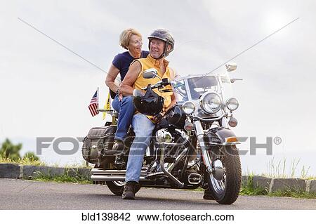 Stock Image - Older Caucasian couple smiling on motorcycle. Fotosearch