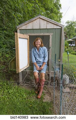 Stock Image - Older Caucasian woman smiling at chicken coop. Fotosearch