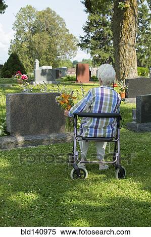 Stock Photography - Older Caucasian woman visiting grave in cemetery. Fotosearch