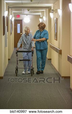 Stock Photo - Older Caucasian woman walking with nurse in nursing home. Fotosearch