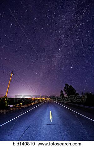 Paved road under starry night sky illuminated by headlights View Large Photo Image Stock Photo - Paved road under starry night sky illuminated by headlights. Fotosearch