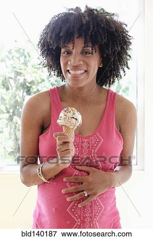 Stock Photo - Pregnant African American mother eating ice cream cone. Fotosearch
