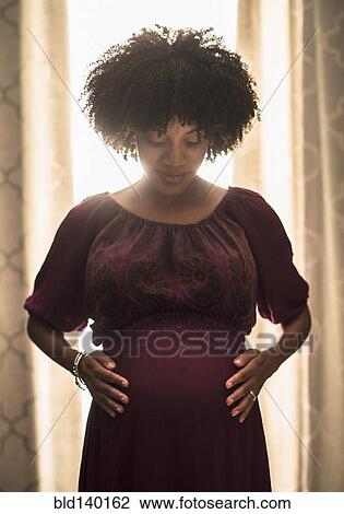 Stock Image - Pregnant African American mother holding her stomach. Fotosearch