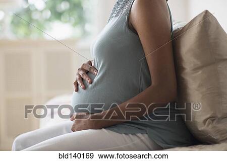Pregnant African American mother holding her stomach View Large Photo Image Stock Photo - Pregnant African American mother holding her stomach. Fotosearch