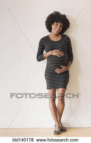 Stock Photo - Pregnant African American mother holding her stomach. Fotosearch