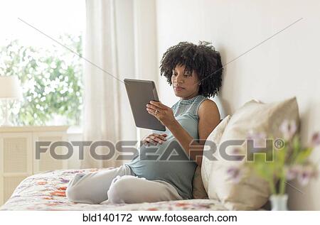 Pregnant African American mother using digital tablet in bed View Large Photo Image Stock Image - Pregnant African American mother using digital tablet in bed. Fotosearch