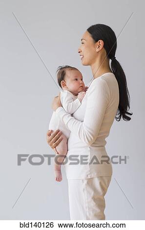 Profile of Asian mother holding baby View Large Photo Image Stock Photograph - Profile of Asian mother holding baby. Fotosearch