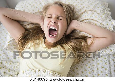 Shouting Caucasian girl covering her ears on bed View Large Photo Image Stock Photography - Shouting Caucasian girl covering her ears on bed. Fotosearch