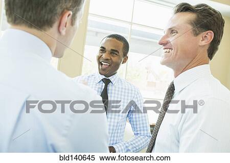 Smiling businessmen talking in office View Large Photo Image Stock Photography - Smiling businessmen talking in office. Fotosearch