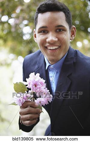 Smiling man in suit holding flower View Large Photo Image Stock Photography - Smiling man in suit holding flower. Fotosearch