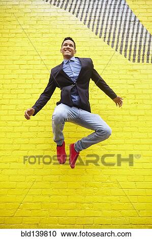 Smiling man jumping for joy near bright yellow wall View Large Photo Image Stock Image - Smiling man jumping for joy near bright yellow wall. Fotosearch