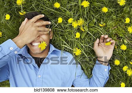 Stock Photo - Smiling man laying in field of flowers. Fotosearch