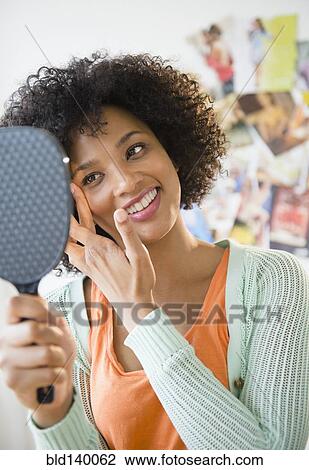Smiling woman admiring herself in mirror View Large Photo Image Stock Image - Smiling woman admiring herself in mirror. Fotosearch